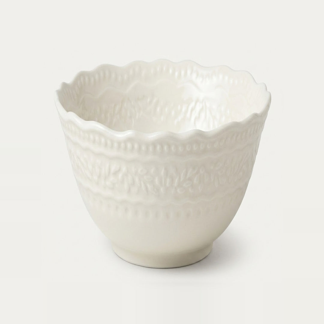An off-white ceramic bowl with a scalloped rim and embossed decorative patterns, shown on a clean white background.