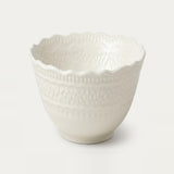 An off-white ceramic bowl with a scalloped rim and embossed decorative patterns, shown on a clean white background.
