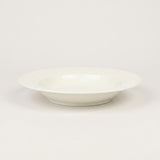 A white ceramic bowl with a subtle textured pattern on the outer rim, photographed against a seamless light gray background.