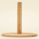 A minimalist bamboo pole stand with a round wooden base, photographed against a clean, solid cream background.
