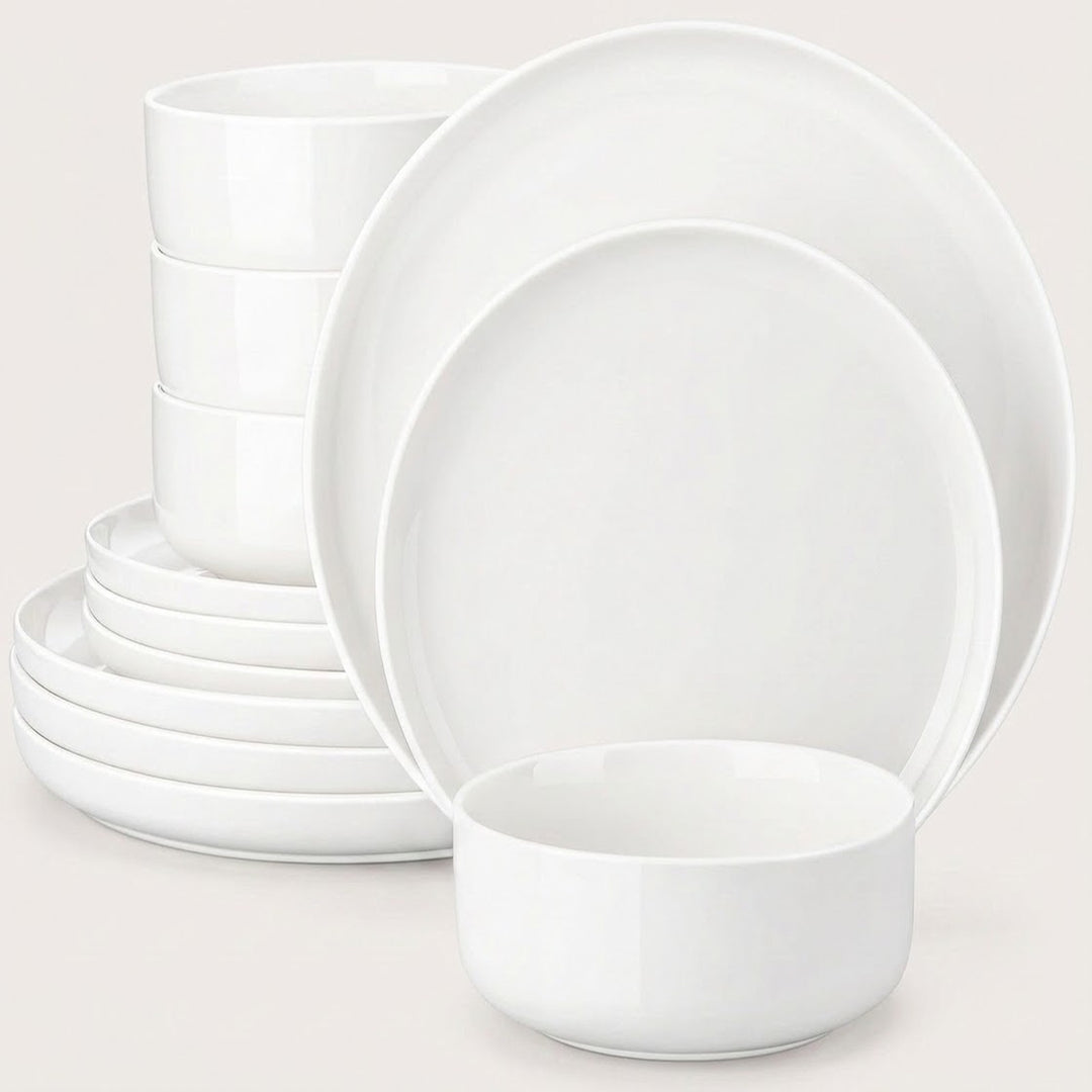 A white ceramic dinnerware set including plates and bowls, arranged on a light beige background.