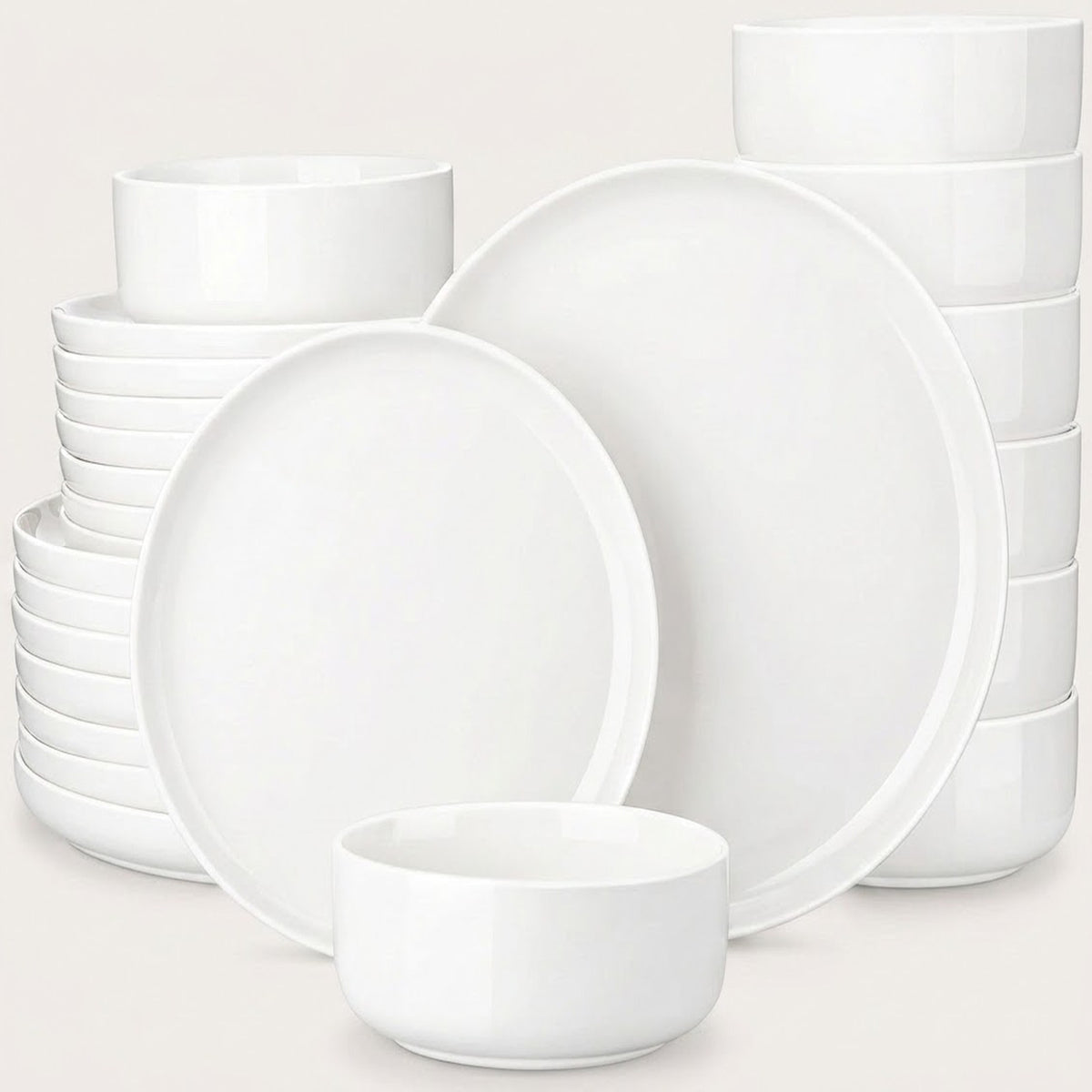 A set of white ceramic dinnerware, including plates and bowls, arranged on a light beige background.
