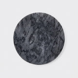 A round black marble coaster with natural veining, shown on a clean white background.