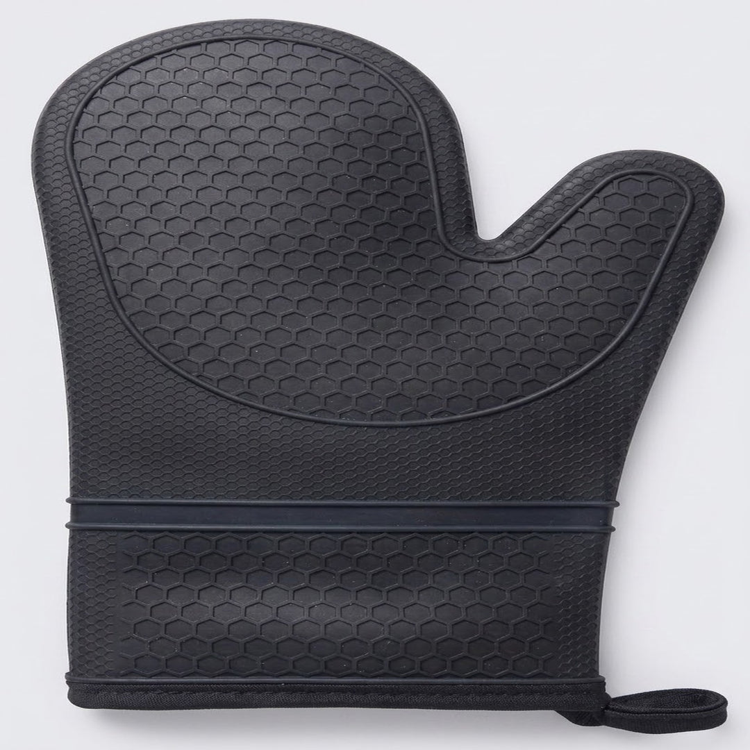 A black oven mitt with a textured honeycomb pattern, featuring a dark elastic band and a small wrist strap, shown on a light gray background.