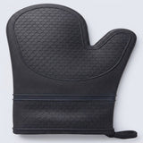 A black silicone oven mitt with a textured honeycomb pattern, featuring a built-in wrist strap and pull tab, shown on a light gray background.