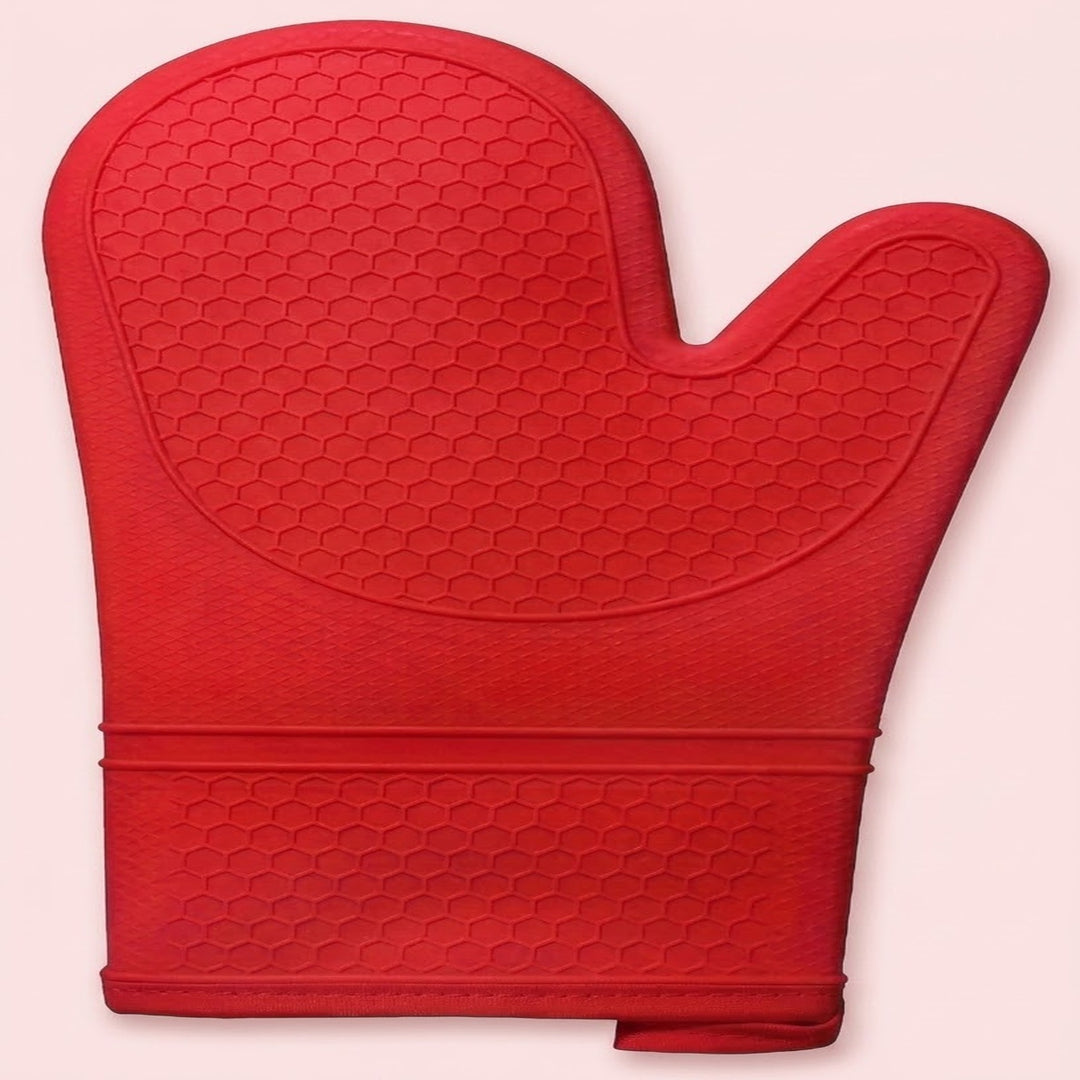 A red silicone oven mitt with a textured honeycomb pattern, shown against a solid pale pink background.