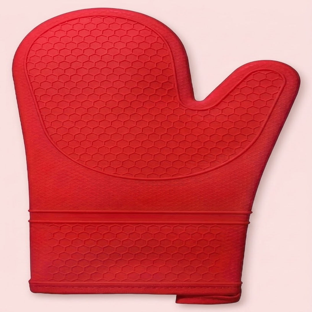 A red silicone oven mitt with a textured honeycomb pattern, shown against a solid pale pink background.