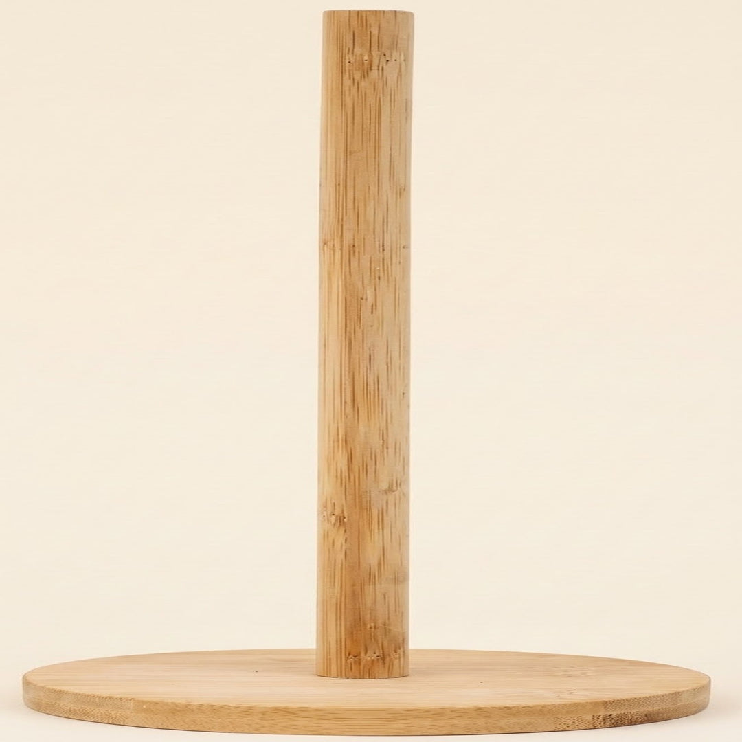 A minimalist bamboo paper towel holder with a round base and a single vertical bamboo pole, shown against a solid cream background.