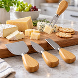 The wooden handle cheese fork serves a cheese cube from a board with the other three tools nearby.