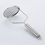 A stainless steel potato masher with a perforated oval head and a smooth cylindrical handle, shown on a light gray background.