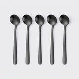 Five matte black spoons arranged in a row on a light gray background.