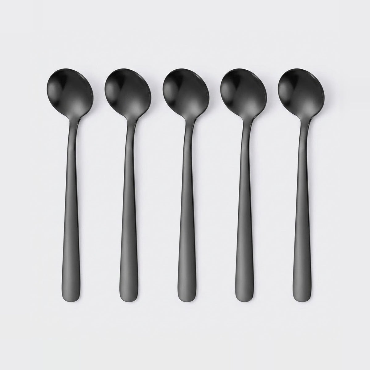 Five matte black spoons arranged in a row on a light gray background.