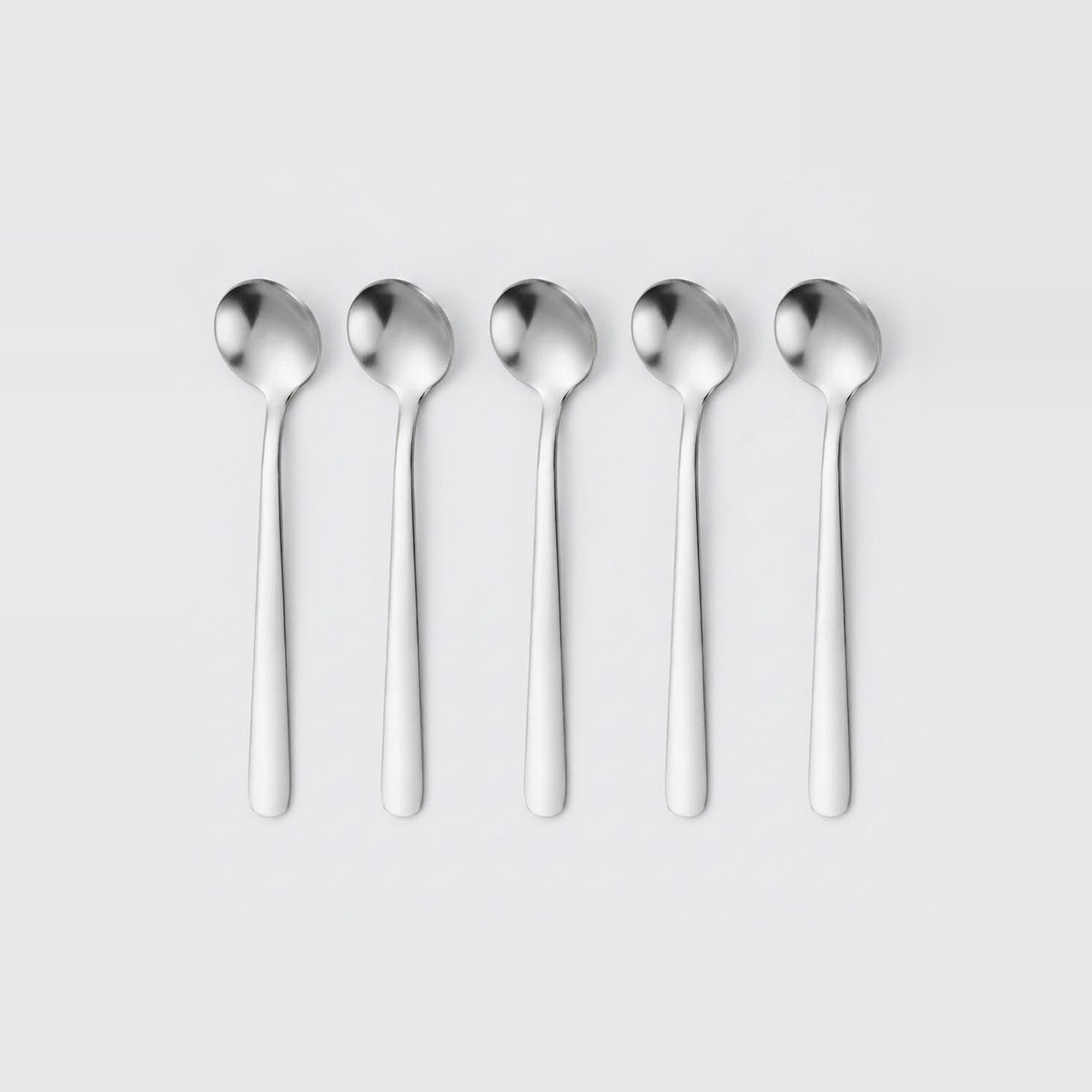 Five identical polished stainless steel spoons aligned in a row on a light gray background.
