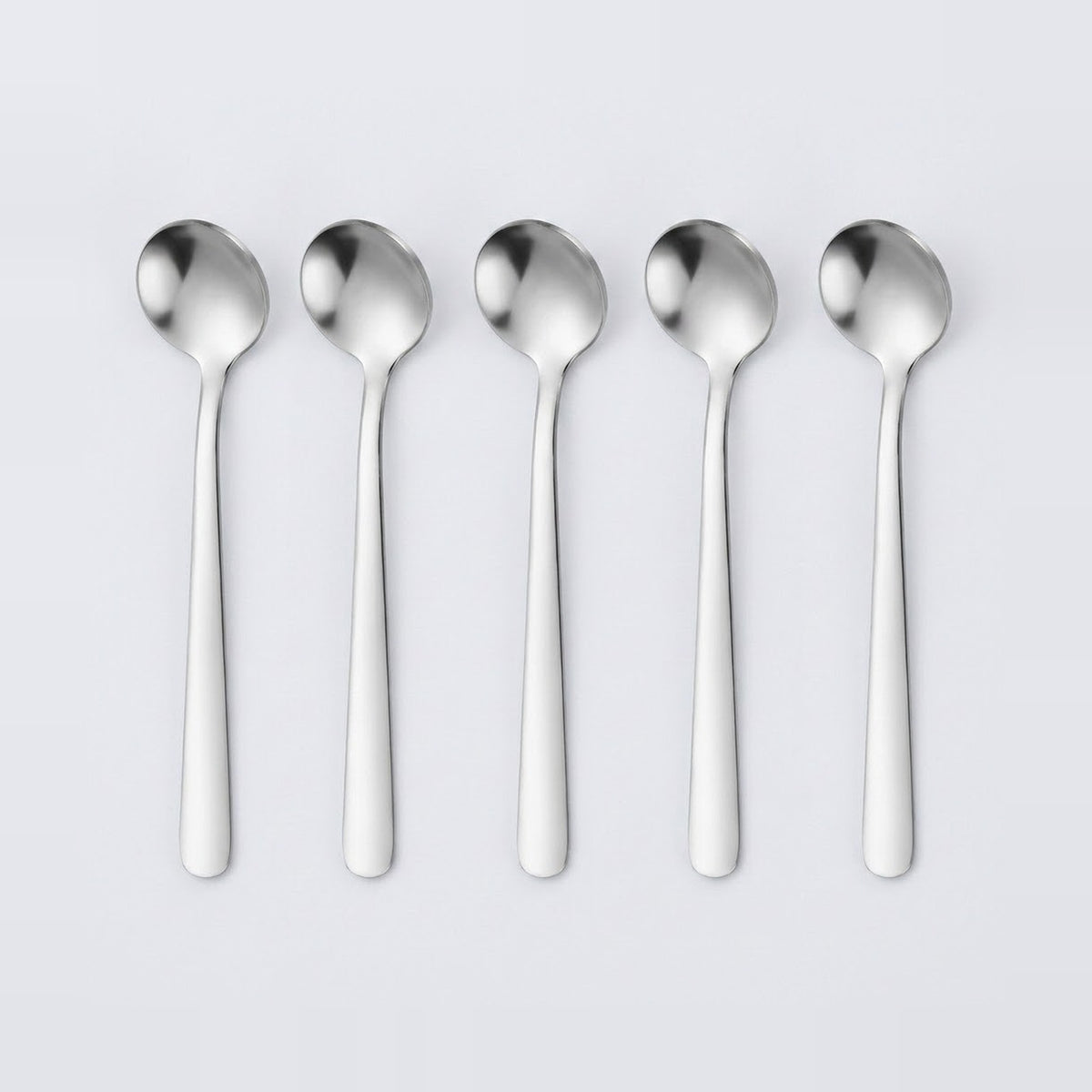 Five stainless steel spoons aligned in a row on a light gray background.