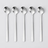 Five polished stainless steel spoons aligned vertically in a row on a light gray background.