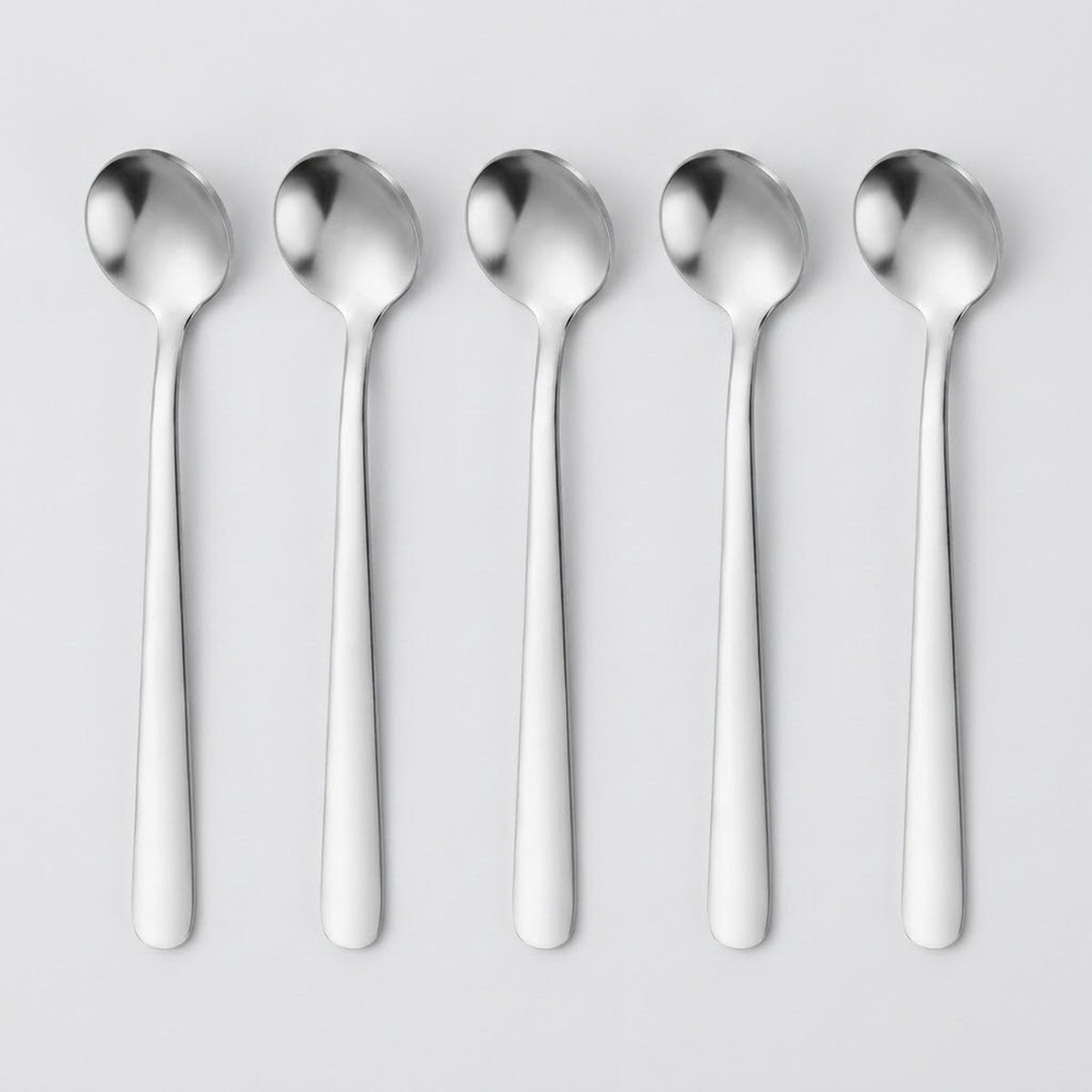 Five polished stainless steel spoons aligned vertically in a row on a light gray background.