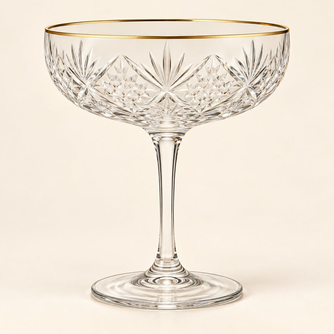 The Gold Rim coupe cocktail glass is centered on a warm ivory studio background.
