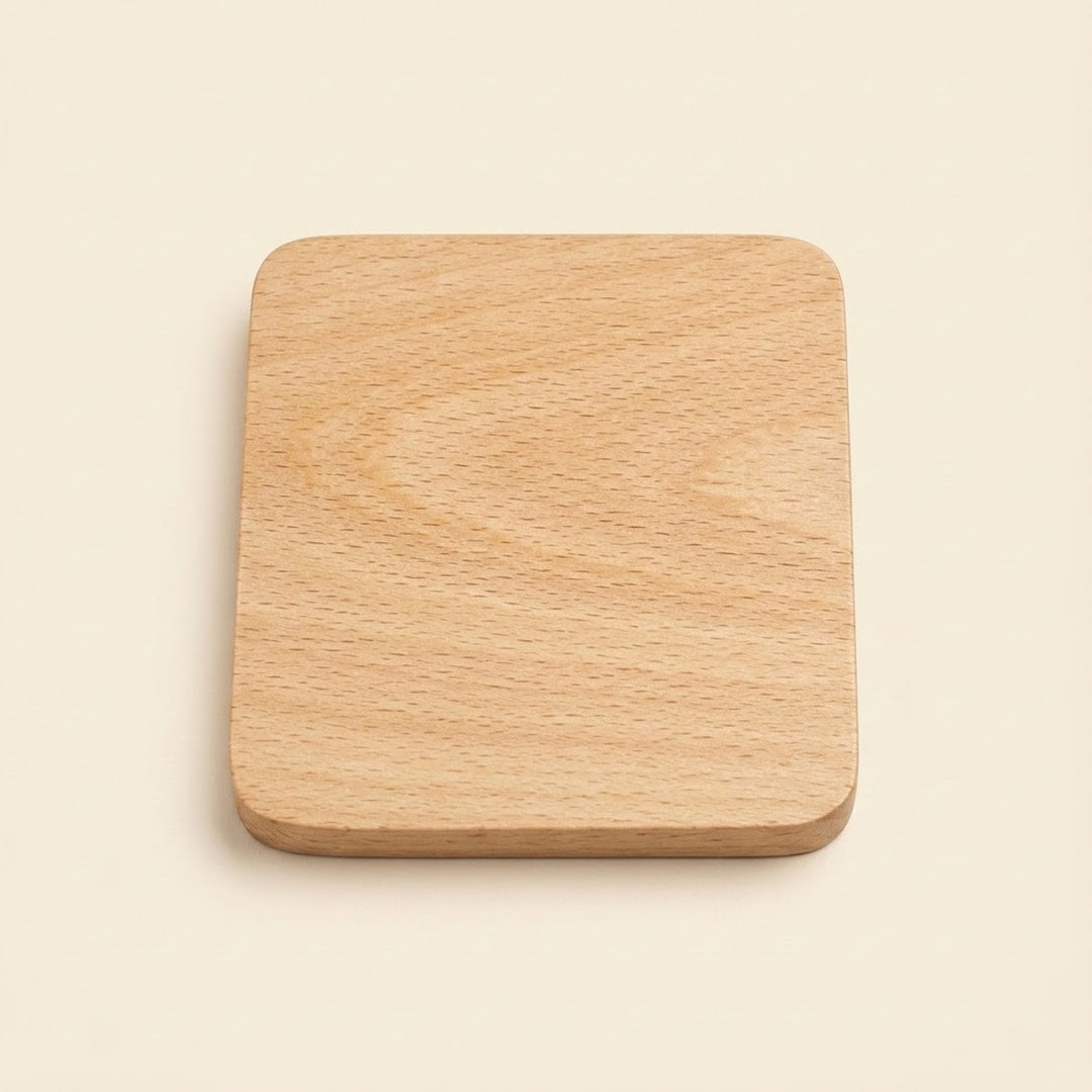 A square wooden coaster with rounded corners, featuring a light natural wood grain texture, centered on a solid cream-colored background.