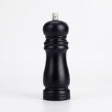 Black wooden pepper grinder with a contoured body and silver top knob stands on a white surface against a white background.