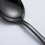 Close-up of a glossy black spoon showing its curved bowl and smooth handle against a pale grey background.