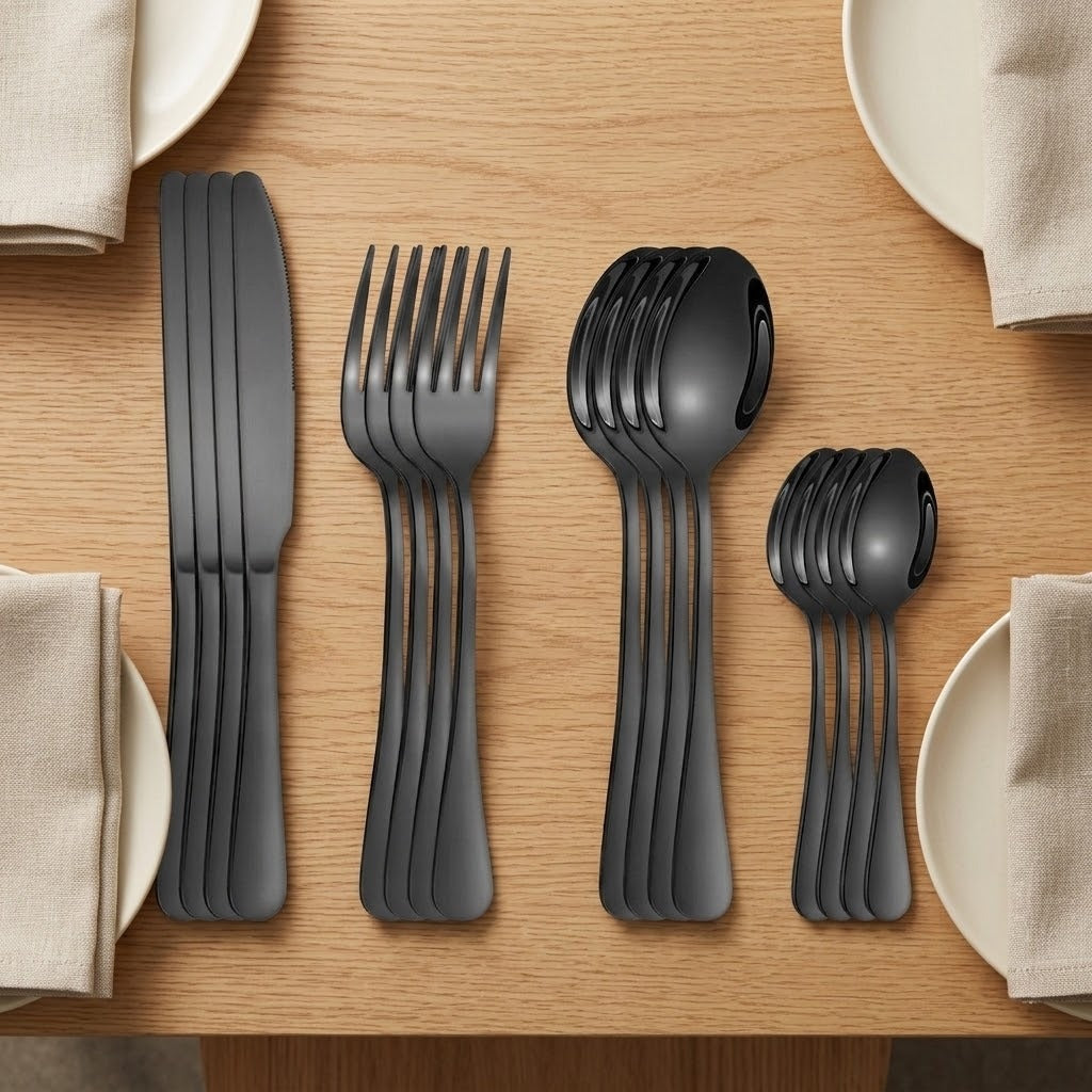Black knives, forks, tablespoons and teaspoons form four overlapping stacks on a wooden table surrounded by cream plates and beige napkins.