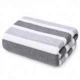 A folded plush towel with alternating dark gray, light gray, and white stripes sits against a plain white background.