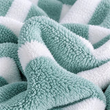 A close-up of loosely gathered mint green and white striped towel fabric shows its dense, fluffy texture.