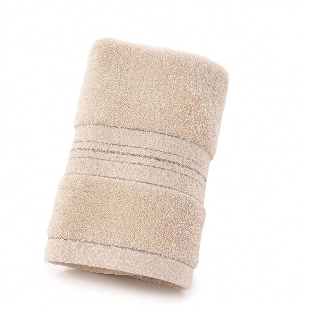 A rolled beige terry towel with thin gray lines across its woven border rests diagonally against a white background.