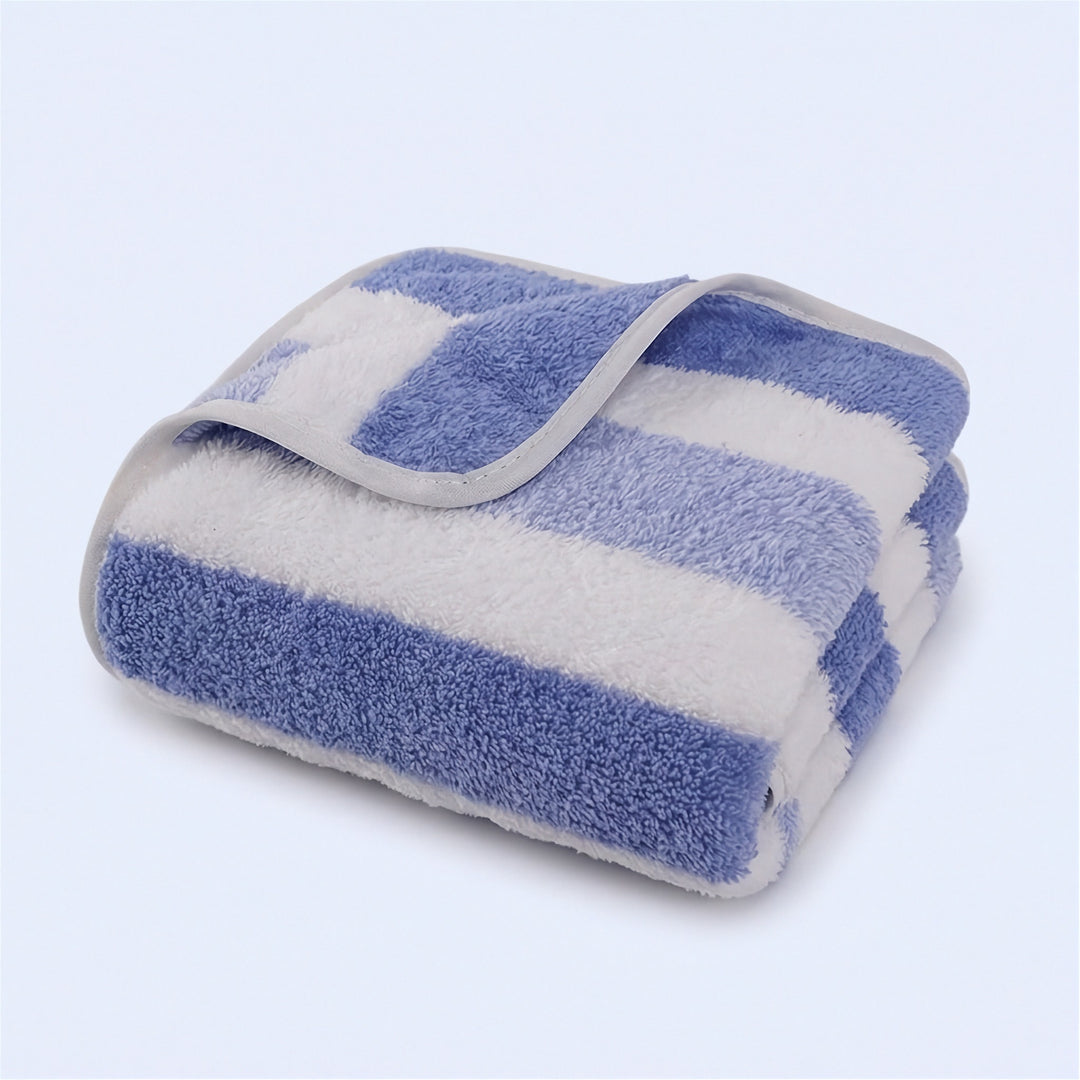 A folded blue and white striped terry towel with pale edge binding rests on a light background.