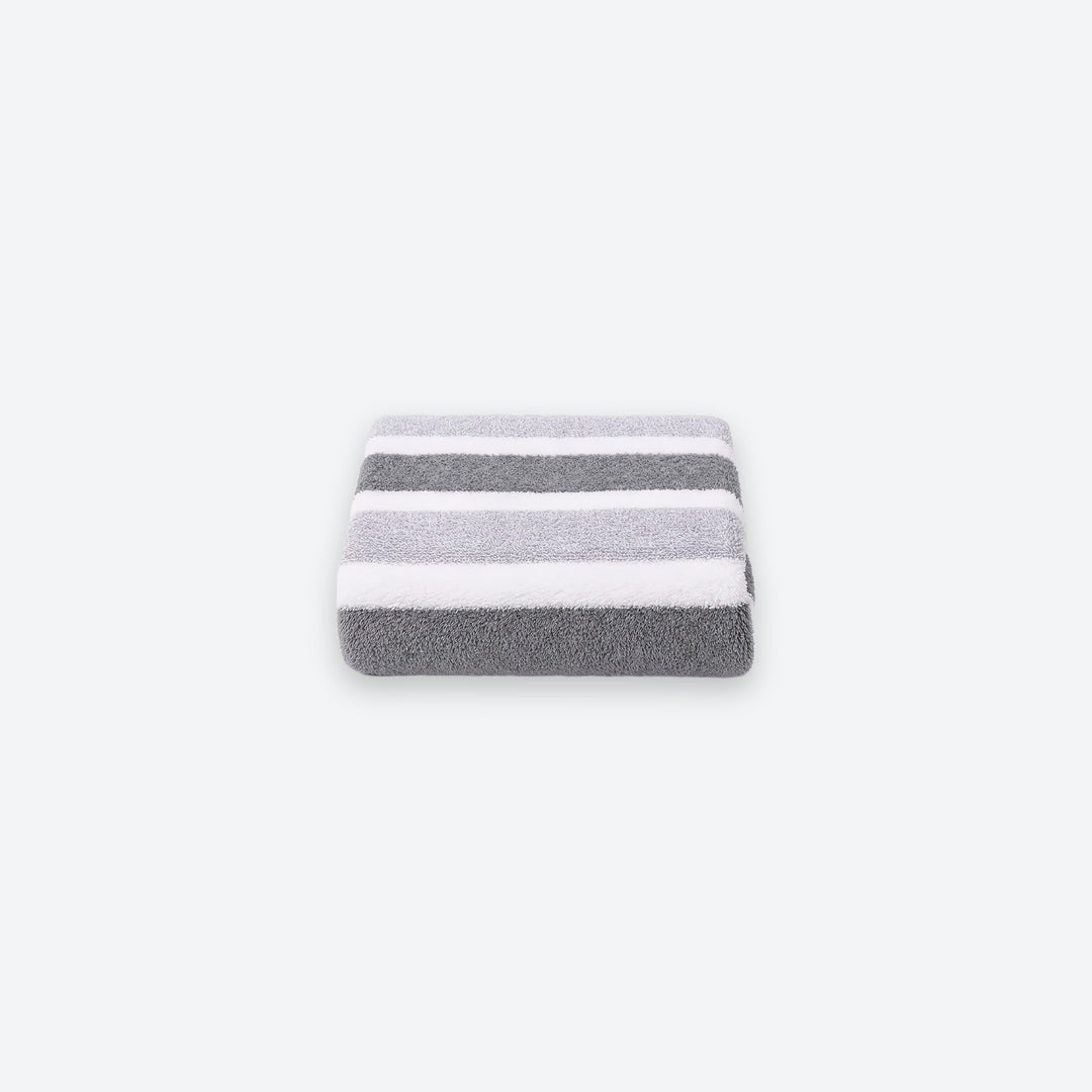 A neatly folded terry towel with broad gray and white stripes sits centered on a light gray background.