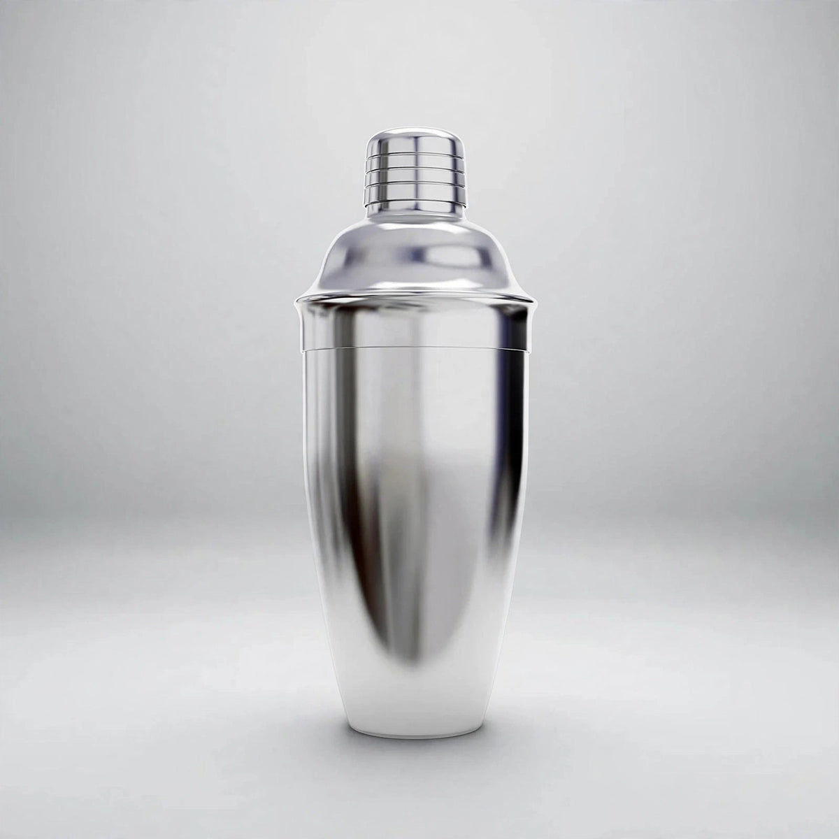 A polished silver cocktail shaker with a domed lid and grooved cap stands upright against a light gray background.