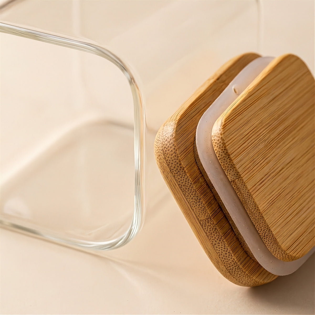 A close-up shows a clear glass jar rim beside a bamboo lid with a white sealing ring on a beige surface.