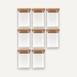 Eight empty clear glass jars with bamboo lids are arranged in rows of three, three, and two against an off-white background.