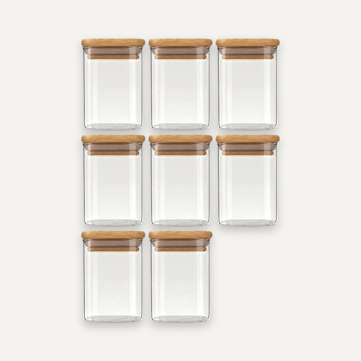 Eight empty clear glass jars with bamboo lids are arranged in rows of three, three, and two against an off-white background.