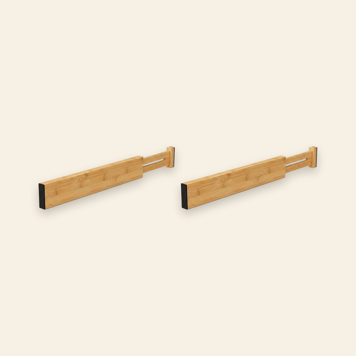Two light brown bamboo drawer dividers with extendable slotted ends and black end pads sit side by side against a cream background.
