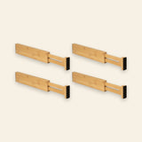 Four light brown bamboo drawer dividers with extendable slotted ends and black end pads form two rows against a cream background.