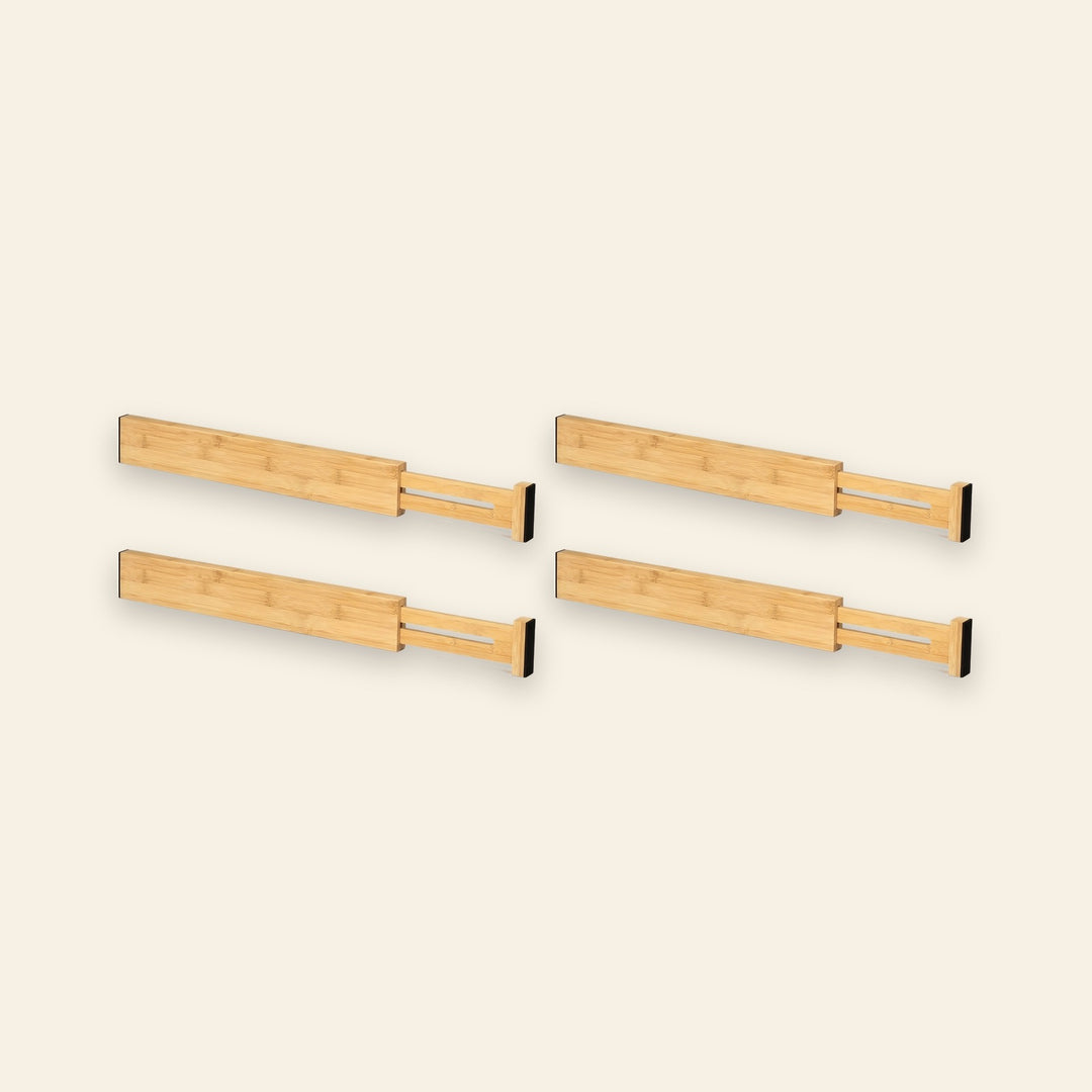 Four natural bamboo drawer dividers with extended slotted sections and black end pads form two rows against a cream background.