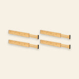 Four natural bamboo drawer dividers with extended slotted sections and black end pads form two rows against a cream background.