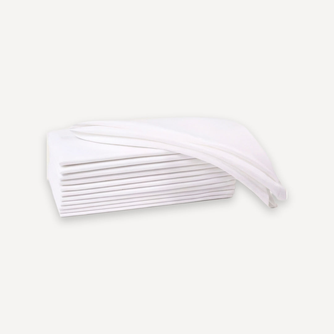 A stack of white, semi-transparent disposable sheets or napkins with a single sheet draped over the top, set against a solid off-white background.