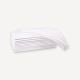 A stack of white, semi-transparent disposable sheets or napkins with a single sheet draped over the top, set against a solid off-white background.