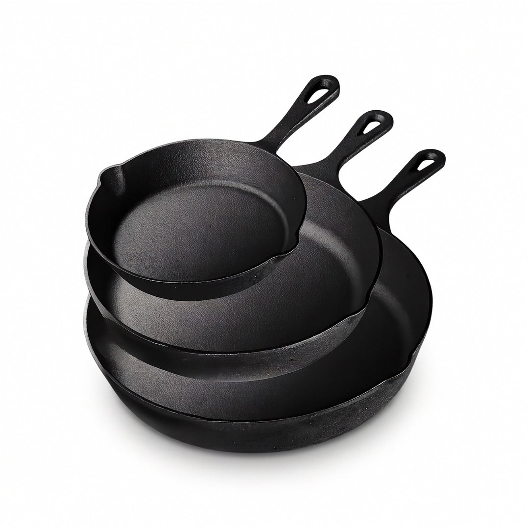 Three black cast iron skillets nest together against a white background, with long handles and pouring spouts visible.