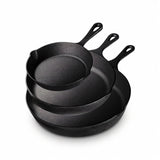 Three black cast iron skillets nest together against a white background, with long handles and pouring spouts visible.