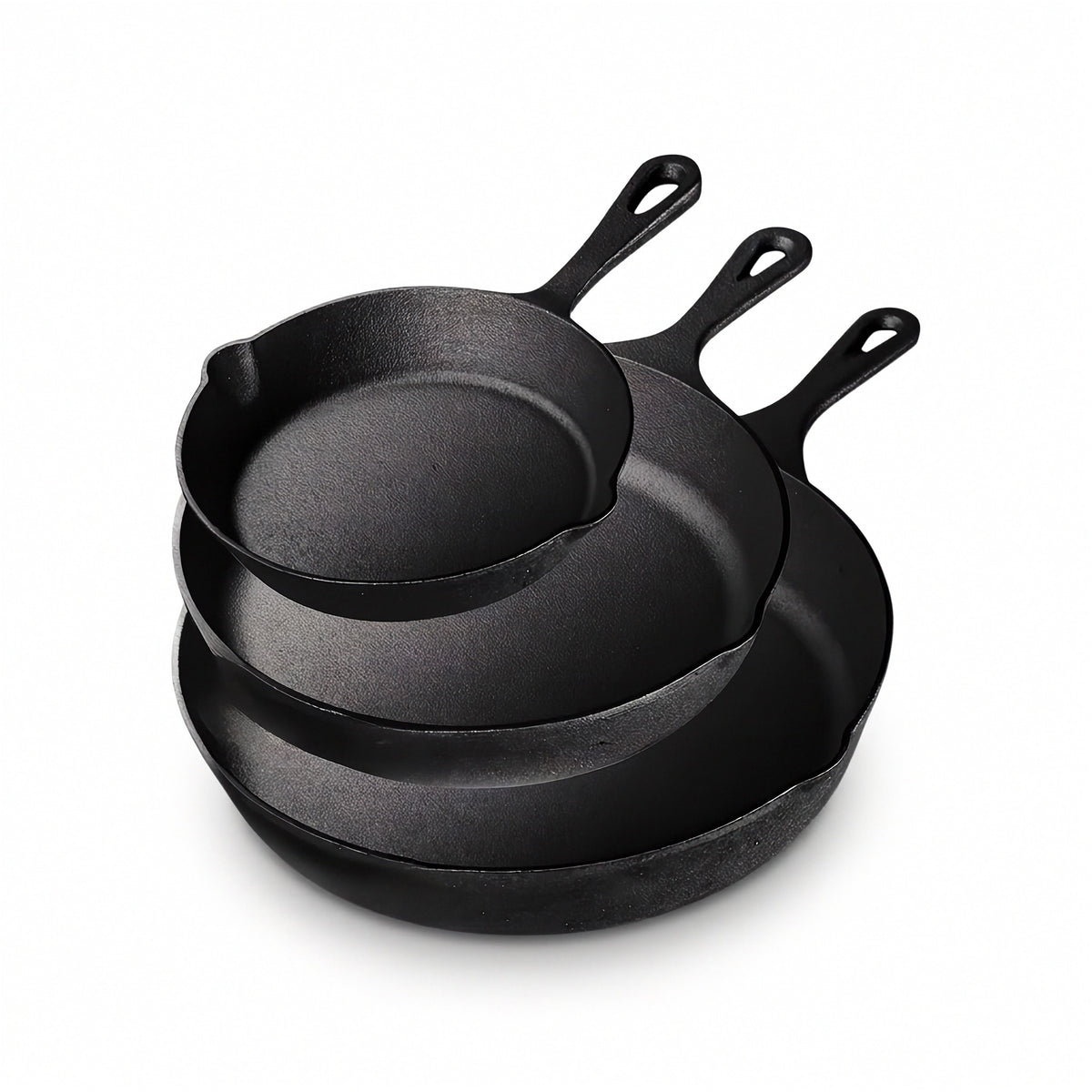 Three black cast iron skillets nest together against a white background, with long handles and pouring spouts visible.