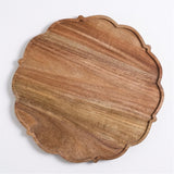 A scalloped round wooden serving board with a rich brown wood grain pattern, photographed from a top-down angle on a clean white background.