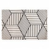 A rectangular area rug with a modern geometric pattern of black hand-drawn lines forming hexagons and diamonds on an off-white background.