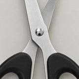 Close-up of the brushed stainless steel blades and metal pivot screw of the black-handled scissors