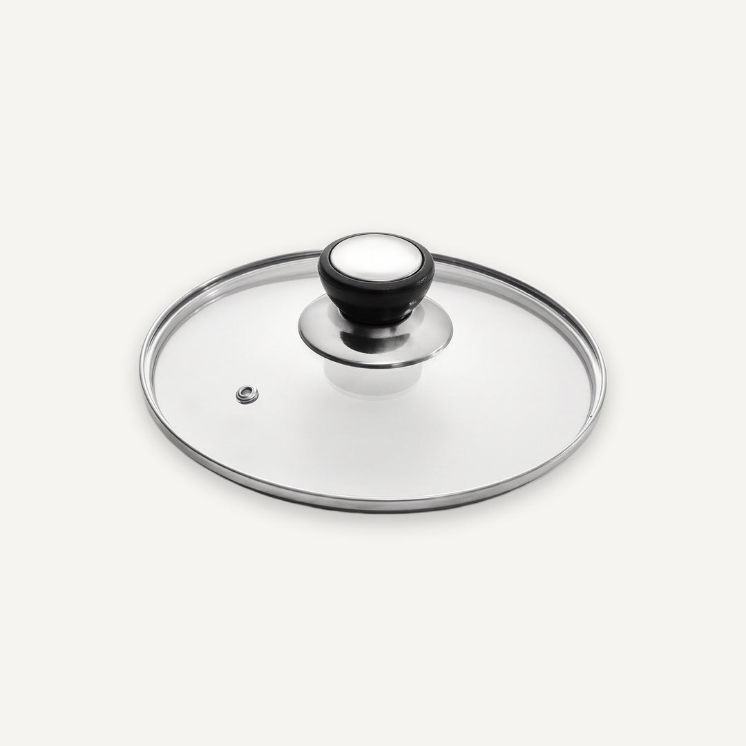 A clear glass lid with a polished silver metal rim and a black-and-white knob, shown on a light gray background.