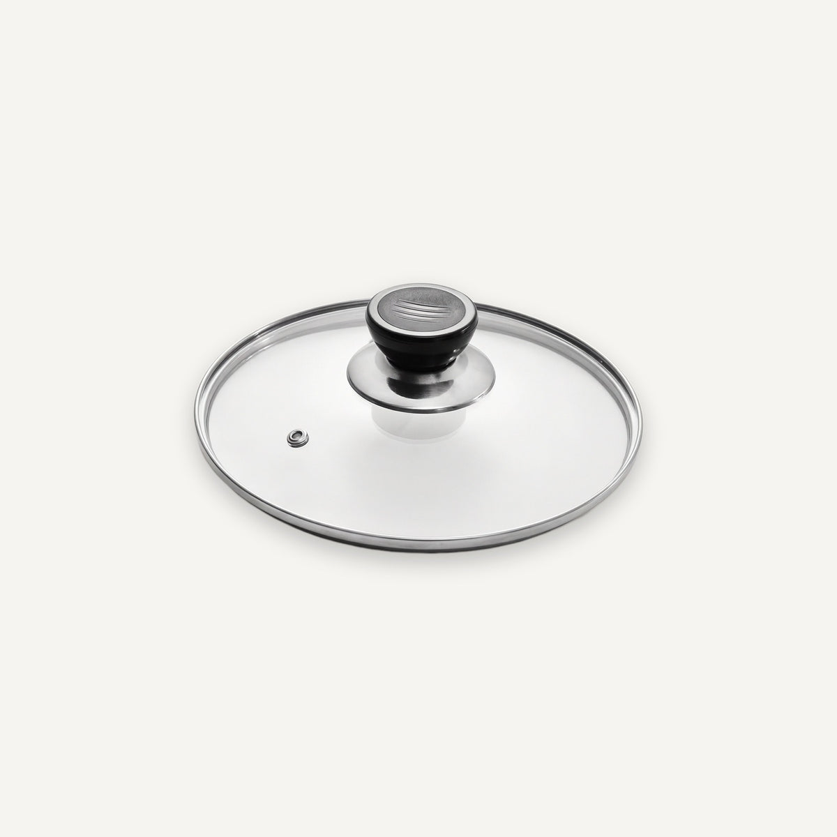 A clear glass cookware lid with a brushed silver metal rim and a black-and-silver knob, shown on a clean off-white background.