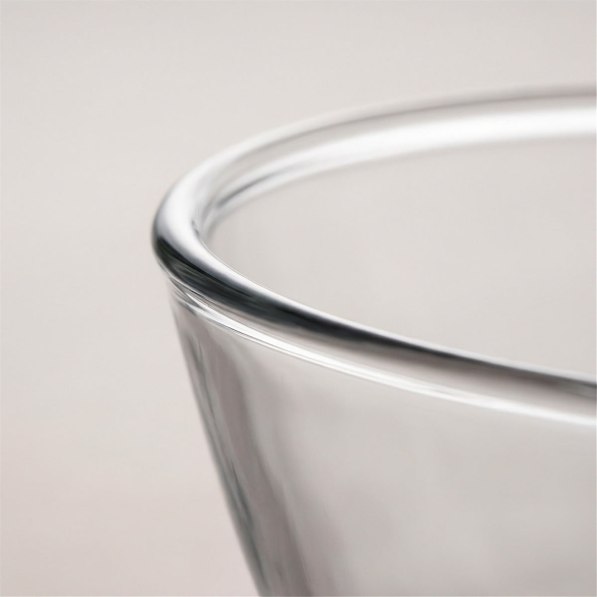 Close-up of a clear glass bowl or cup rim against a light neutral background.