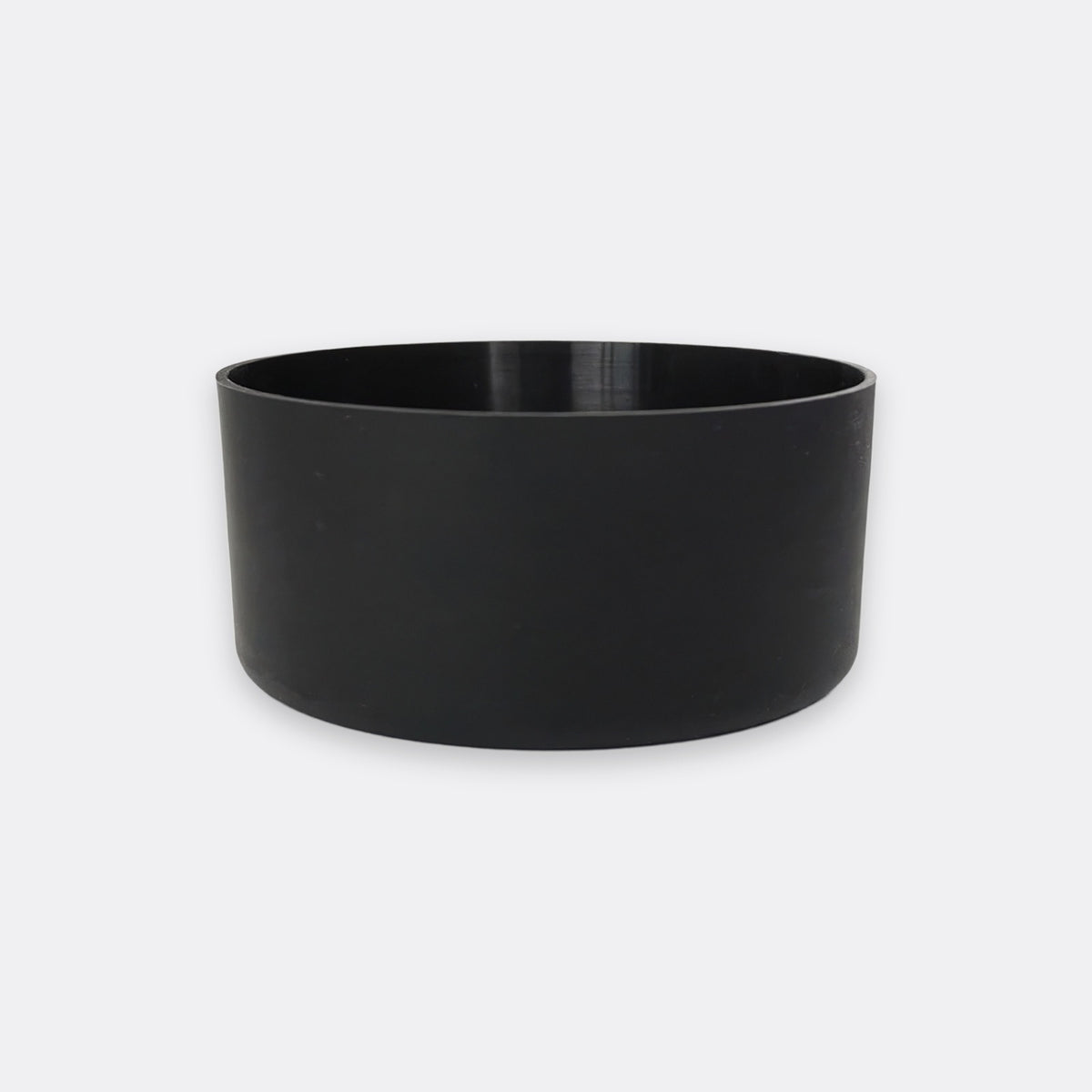 A minimalist black cylindrical planter or bowl with a matte finish, shown against a light gray background.